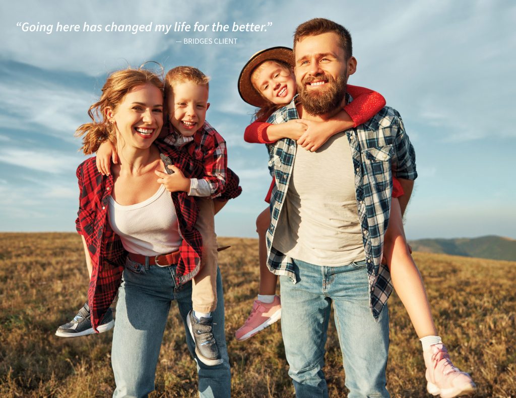 A family of four smiling, with two children on the adults' backs, enjoys storytelling time outdoors on a grassy field under a clear sky. A quote from a client is in the top left corner.